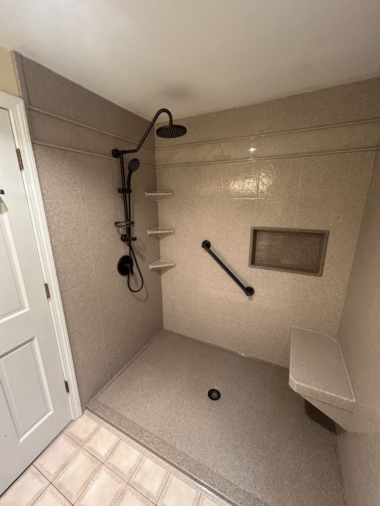 walk-in shower with taupe Luxury Bath wall system, matte black rain showerhead, grab bar, recessed niche, and bench
