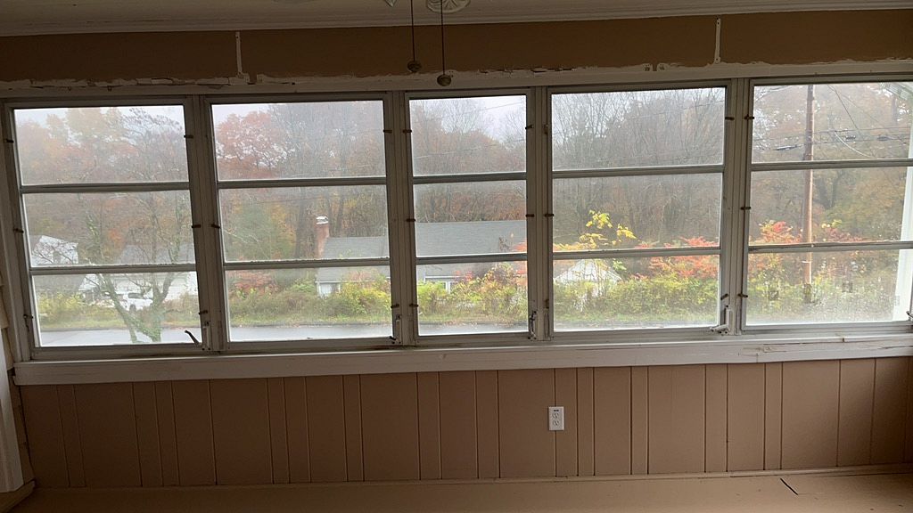 a wall of aging windows with horizontal glass louvers in an enclosed sunroom