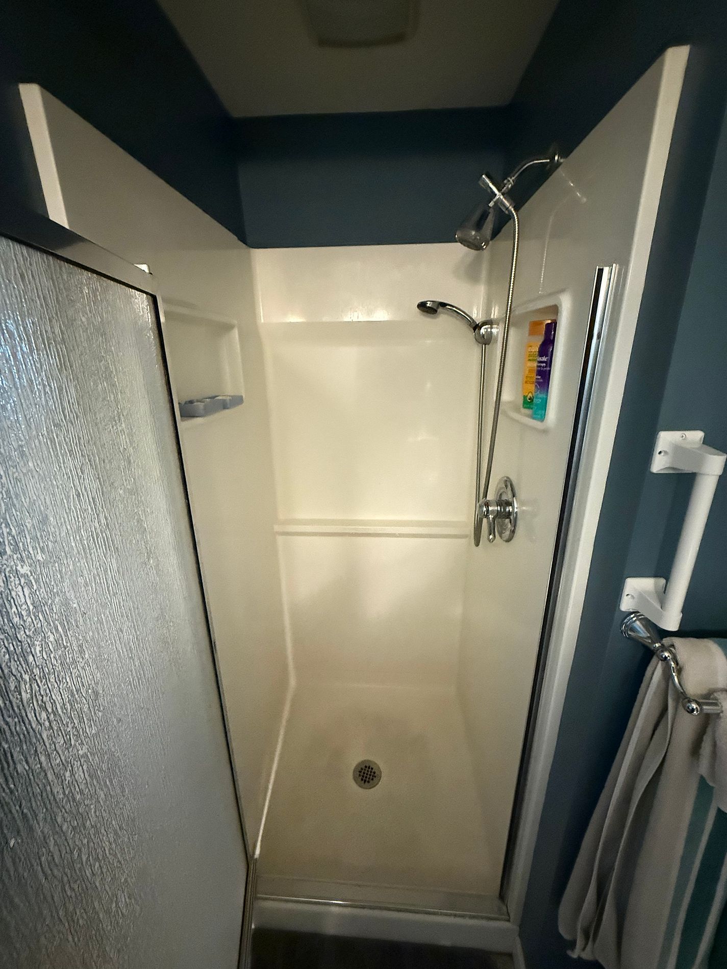 Existing walk-in shower on Farmington Ave Berlin CT showing original white fiberglass surround chrome framed door and navy wall paint before Nu-Face consultation