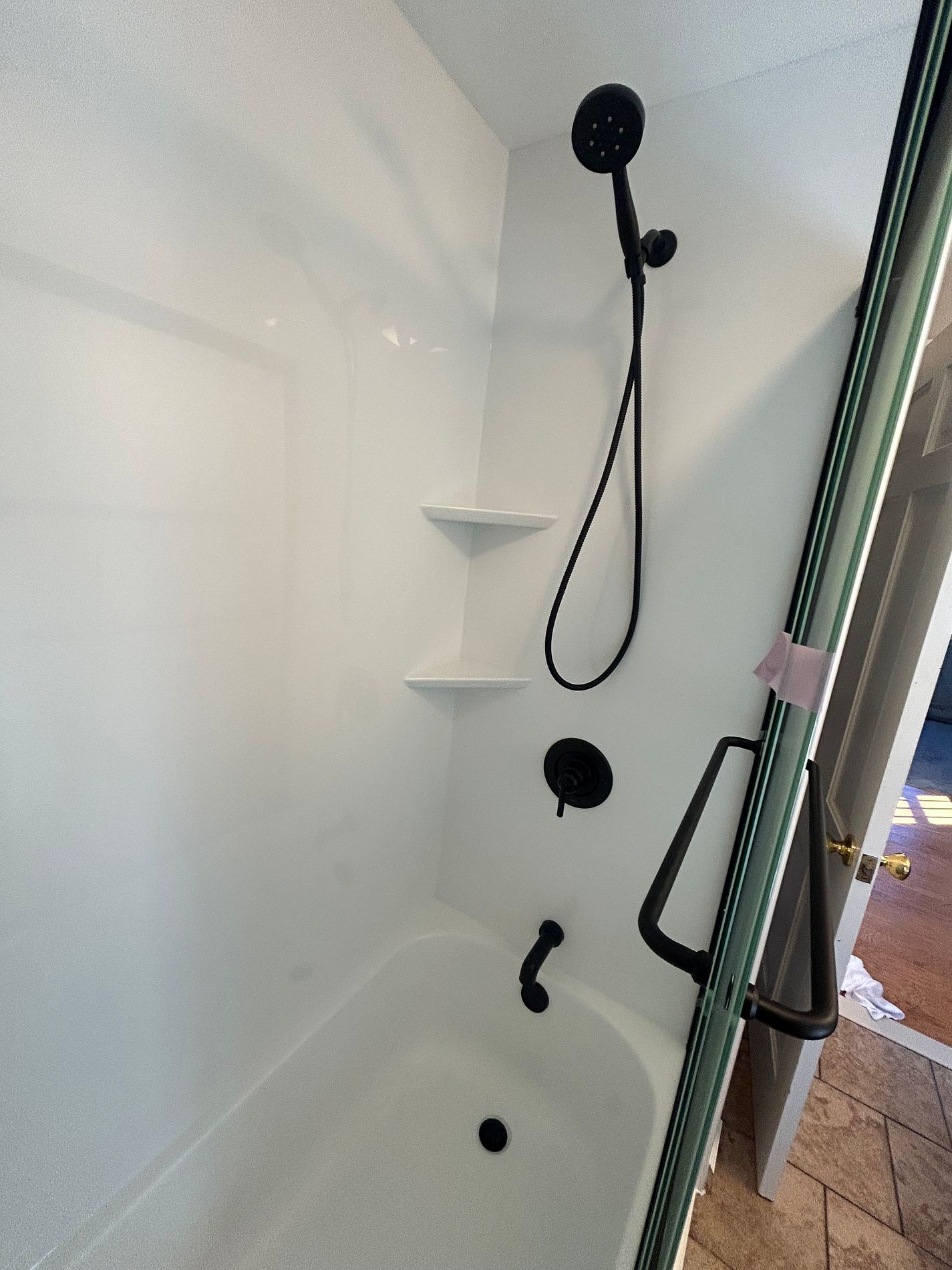 Interior view of Valley Drive Berlin CT updated tub enclosure showing new Luxury Bath acrylic wall panel matte black rain head hand shower and corner shelves