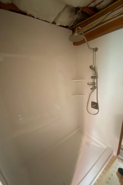 Freshly installed Luxury Bath tub and white acrylic surround on Rod Road Berlin CT with nickel rain head mid-renovation with ceiling open above